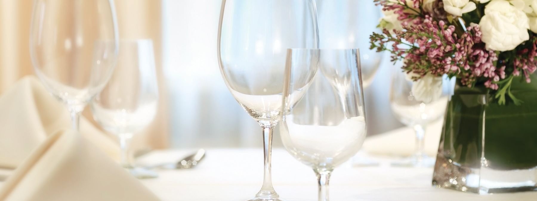 Sophisticated table setting with crystal glassware& white linens, and fresh flowers in Kent meeting room at Warwick New York