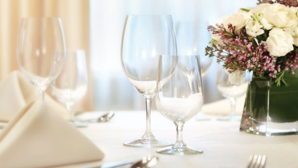 Sophisticated table setting with crystal glassware& white linens, and fresh flowers in Kent meeting room at Warwick New York