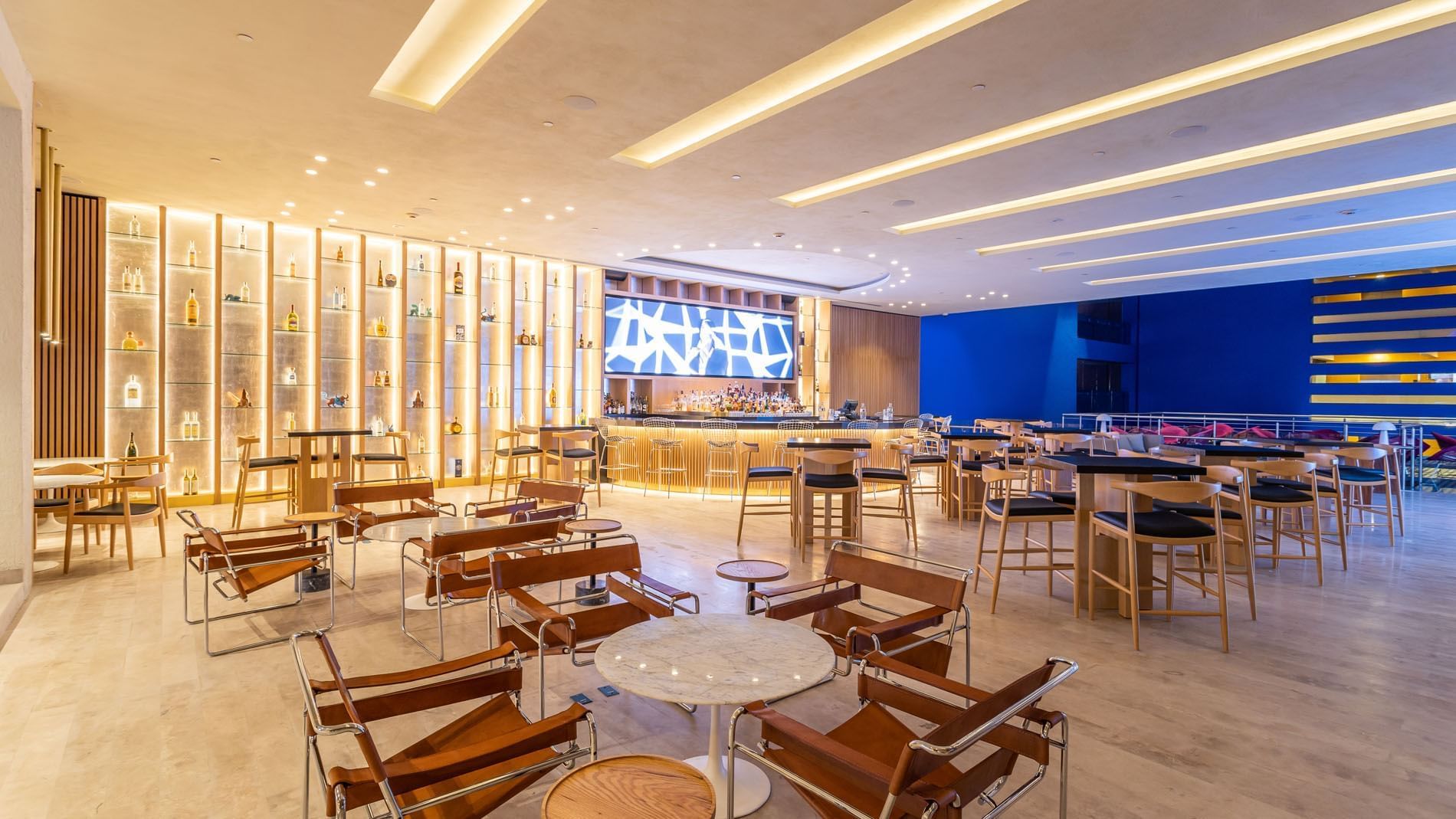 Blue Bar with leather chairs, golden shelving, and bright blue walls at Camino Real Polanco Mexico