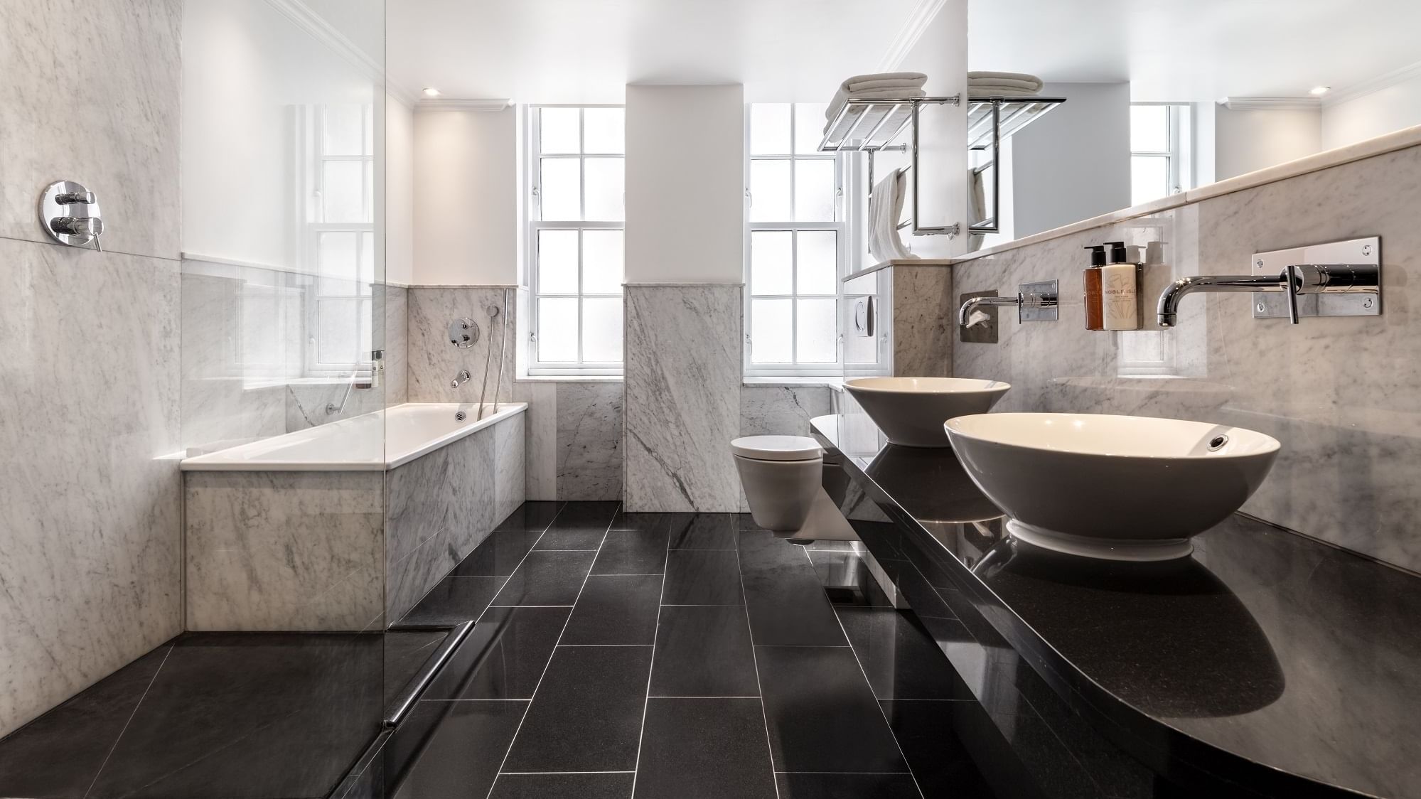 Sleek bathroom in the Collection Deluxe Room at The May Fair Hotel with dual vessel sinks, large mirrors, and a bathtub