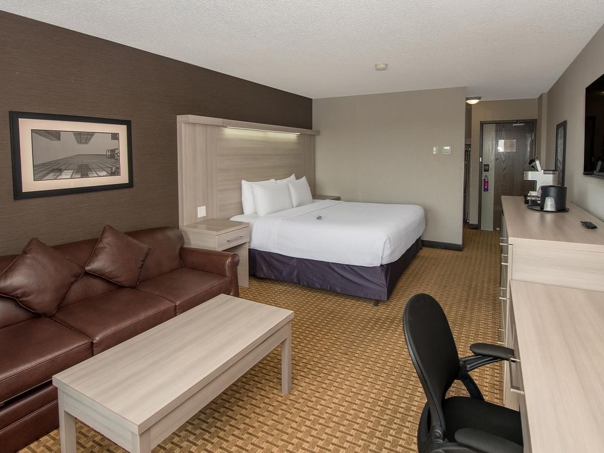 Coast Premium King room with king bed, brown leather sofa, work desk, and wall-mounted TV at Coast Calgary University Area Hotel by APA
