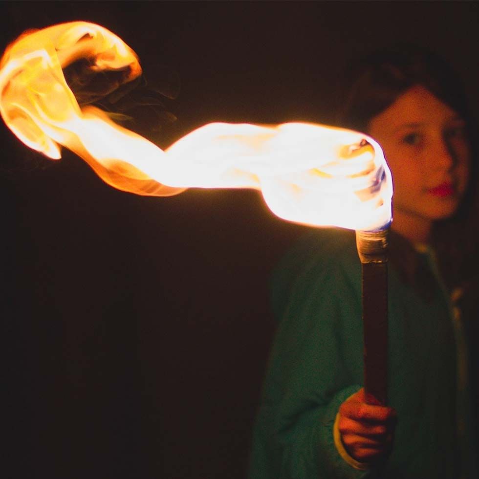 A girl holding a fire torch at  Falkensteiner Hotels