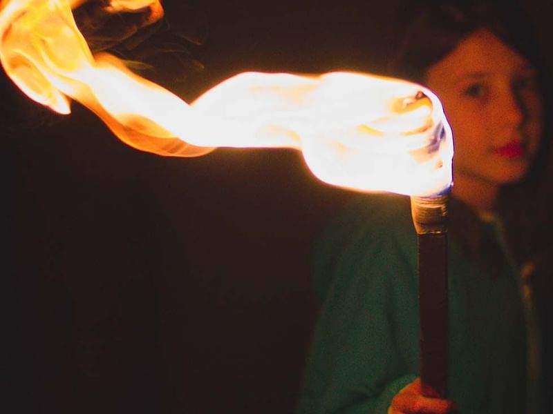 A girl holding a fire torch at  Falkensteiner Hotels