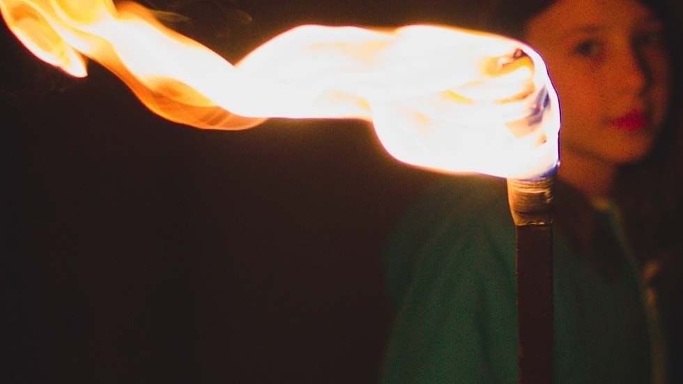 Girl with a fire torch against a dark background near Falkensteiner Hotel Montafon