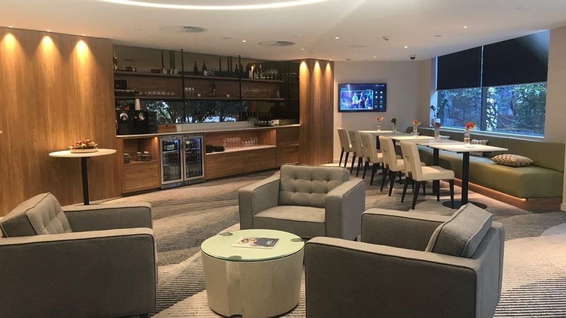 Lounge and bar area with plush seating and carpet floors in the Executive Room with Lounge Access at Pullman Olympic Park