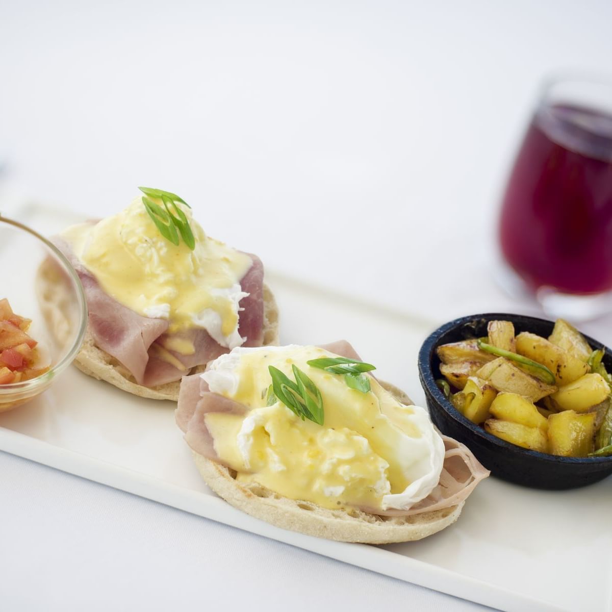 Eggs Benedict on English muffins with ham, hollandaise, and diced tomatoes at Windsong Resort On The Reef