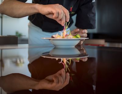 Close-up of chef garnishing dish served in Osteria 31, one of the best restaurants in Lausanne at Starling Hotel Lausanne