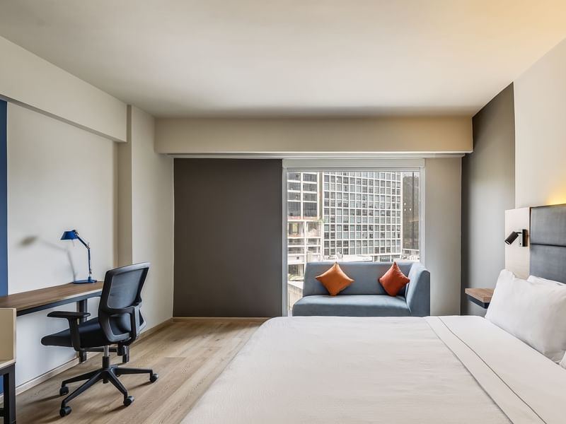 Cozy bed with a work desk and a corner couch in Executive King room at Fiesta Inn