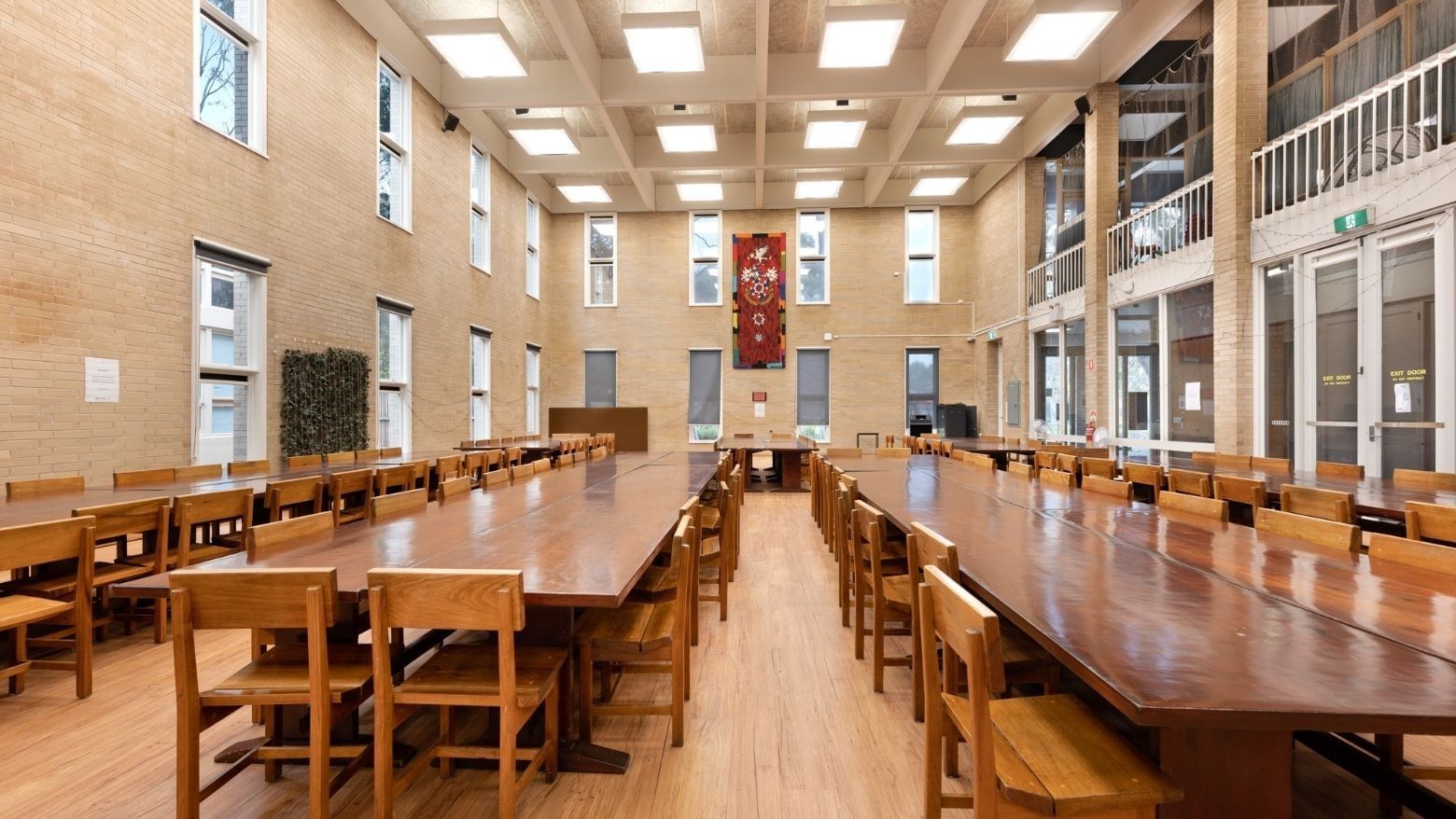 Long wooden tables with chairs in a spacious hall at La Trobe University Glenn College.