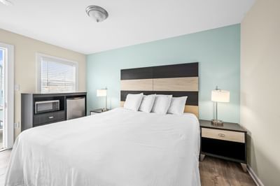 1 King Bed bedroom featuring a king bed, a small fridge, a microwave, and stylish lamps at Madison Beach Motel