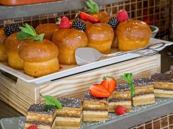 Glazed brioche cakes topped with berries & mint beside sliced layered opera cakes dusted with sugar at Téséo Restaurant & Bar