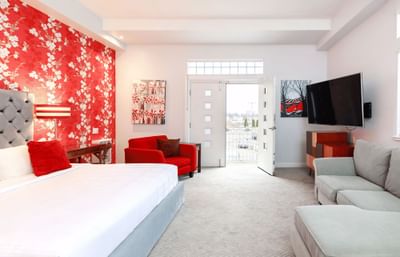 La Rouge Suite with a balcony, bold red accents, king bed, and spacious room with a cozy couch.
