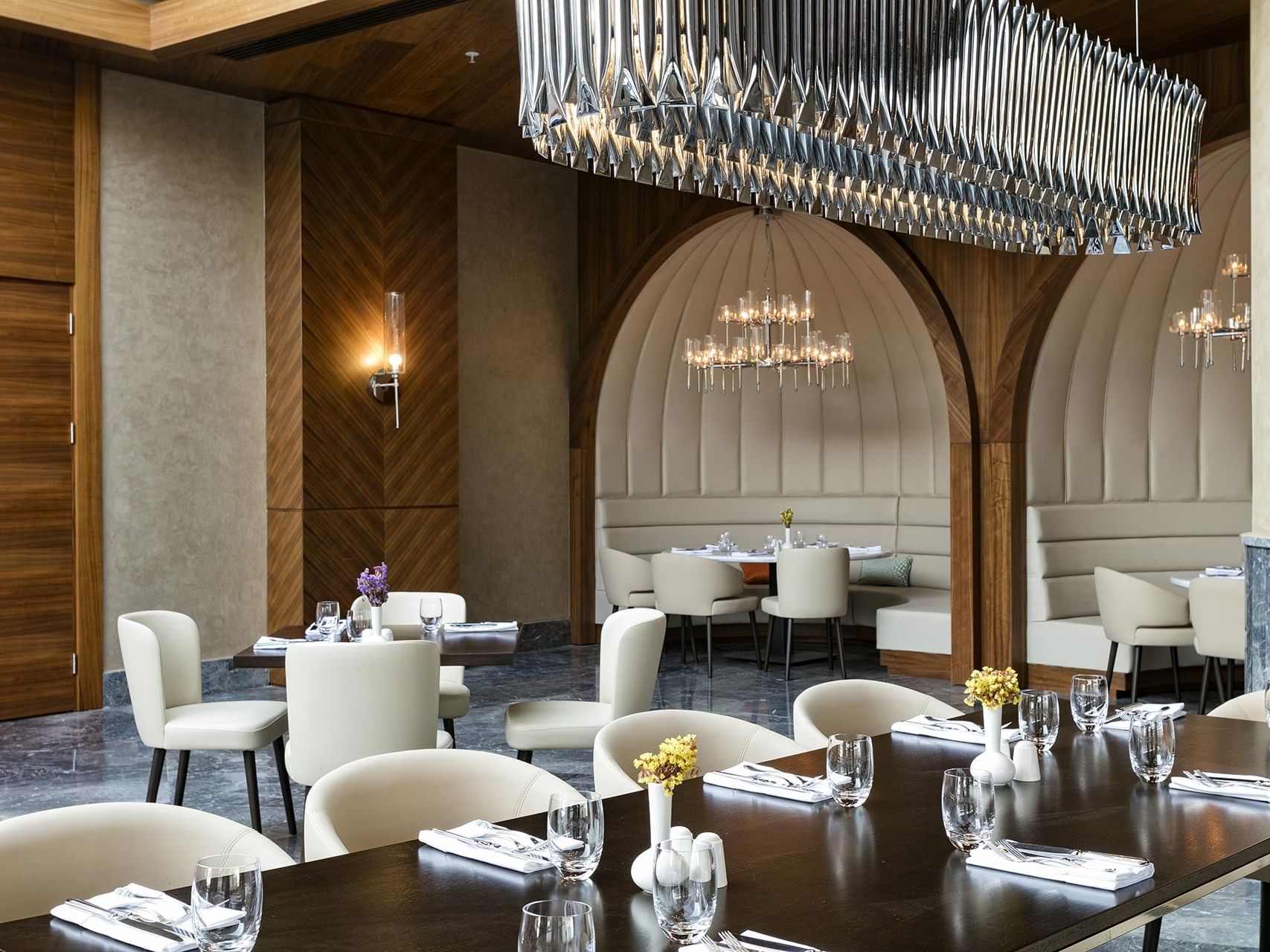 A luxurious restaurant interior at Titanic Luxury Collection Bodrum, adorned with stylish furniture and decorative chandeliers.