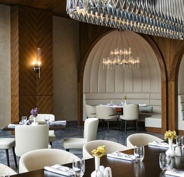 Titanic Luxury Collection Bodrum’da, büyük bir avizeyle aydınlatılan, kavisli locaların üzerinde iki küçük avizenin yer aldığı zarif bir yemek alanı.