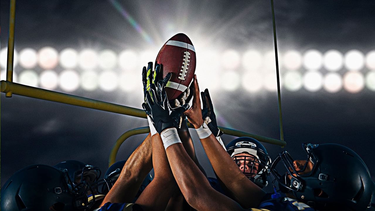 Football players in helmets hold a football above their heads on a sports field in Pullman, WA.