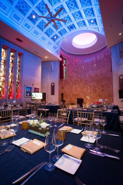 An opulent ballroom at the Bolger Center featuring stained glass windows, high ceilings, and tables set for a gala