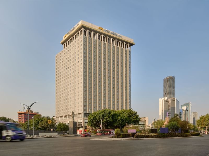 The towering Fiesta Americana building stands prominently in a bustling urban environment, with clear skies