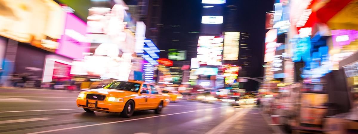 A taxi cab with glowing lights driving at Time Square near Warwick New York