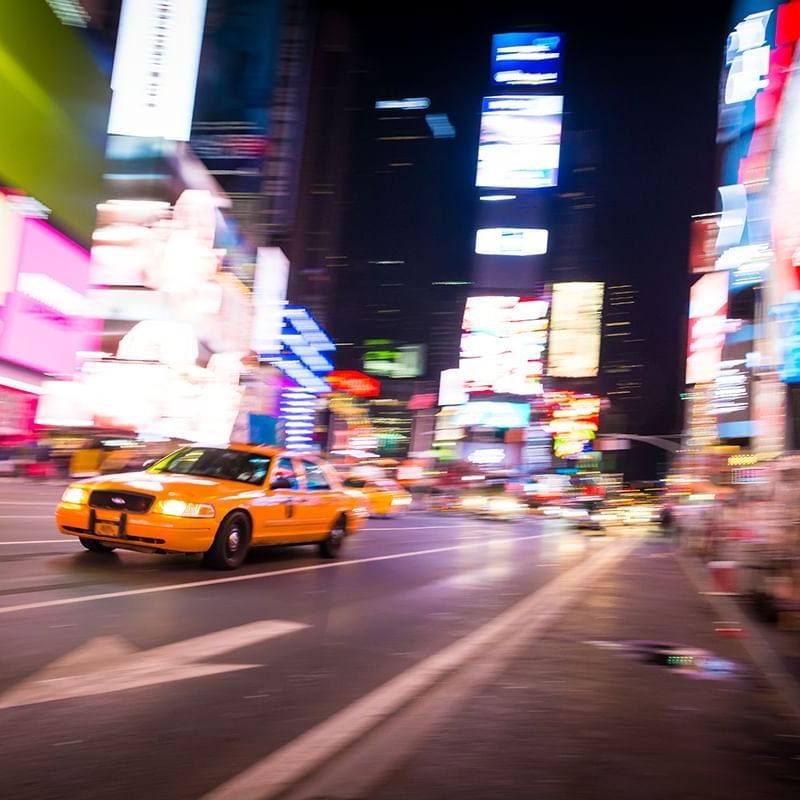 A taxi cab with glowing lights driving at Time Square near Warwick New York