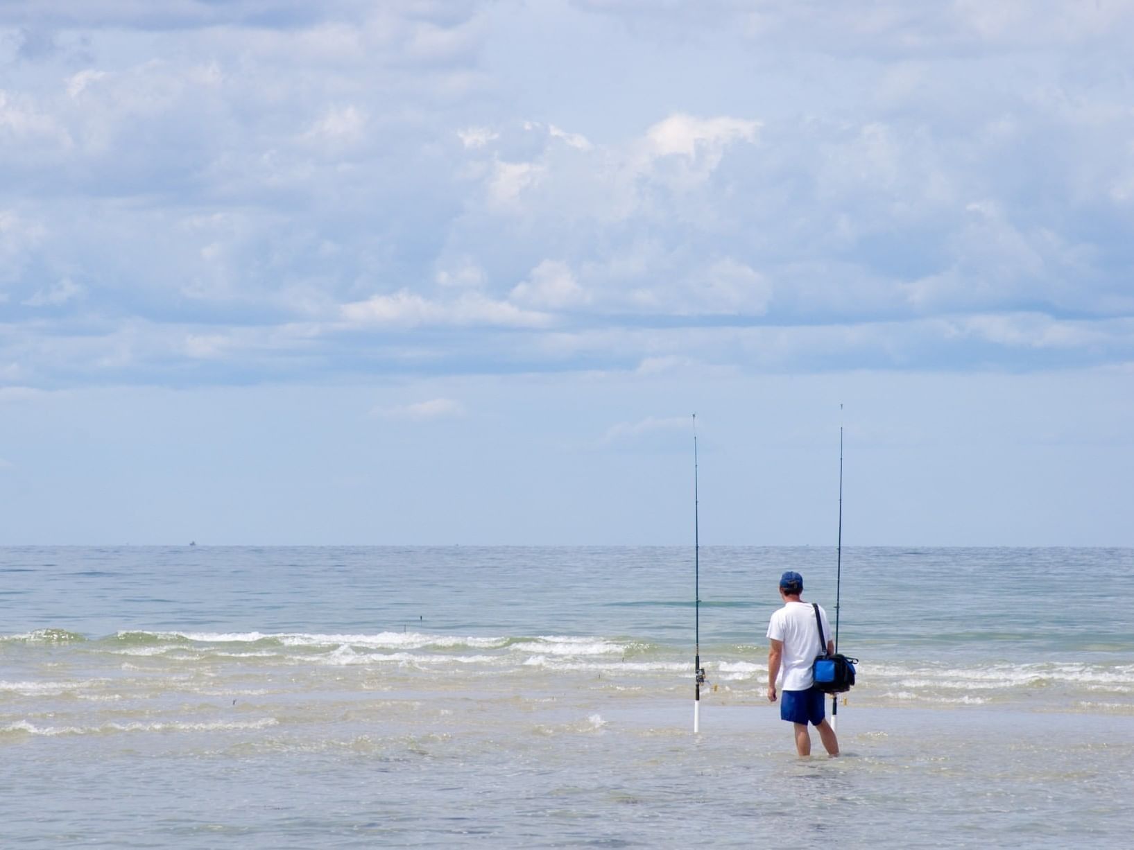 A man standing on the beach by fishing rods near Chatham Tides Resort