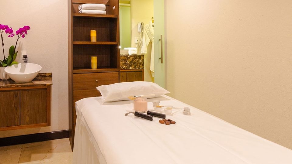 Spa treatment bed with massage tools, pink orchids, and warm candle lighting at Camino Real Pedregal Mexico