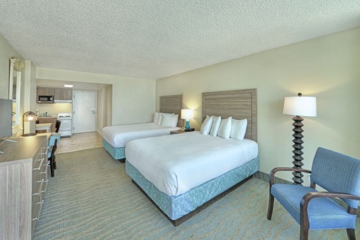 A wide view of an oceanfront efficiency room with two queen beds, a kitchenette, and a sitting area.