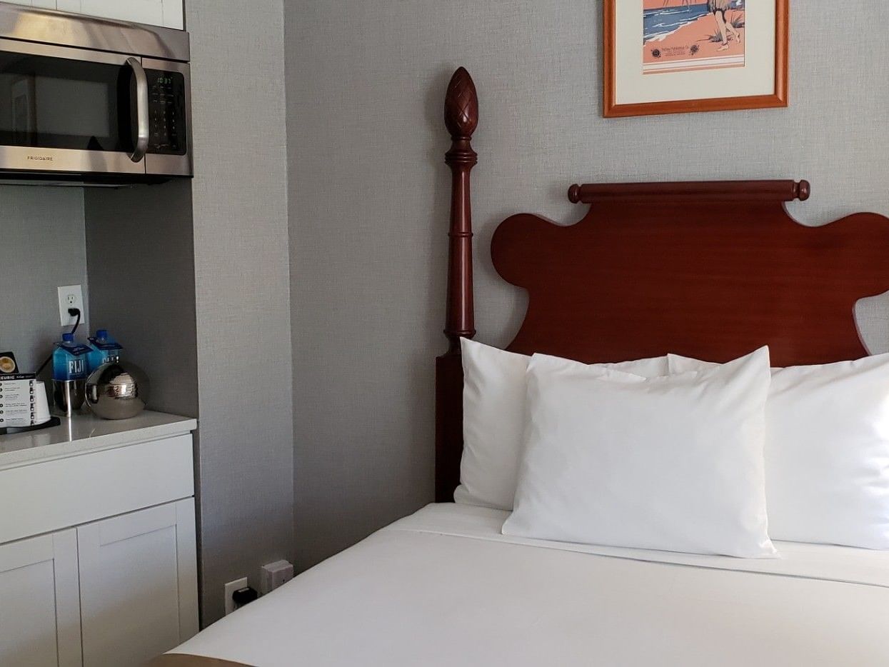 Family Suite with wooden bed, white linens, kitchenette, and coastal artwork at Polynesian Residences in Honolulu