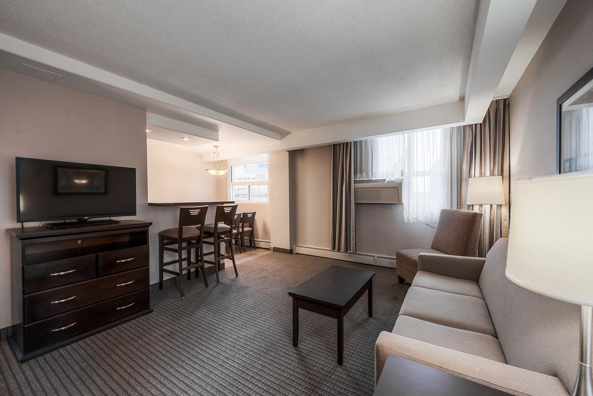 Sitting area with TV and view of bar stools facing into kitchen in our two bedroom suite