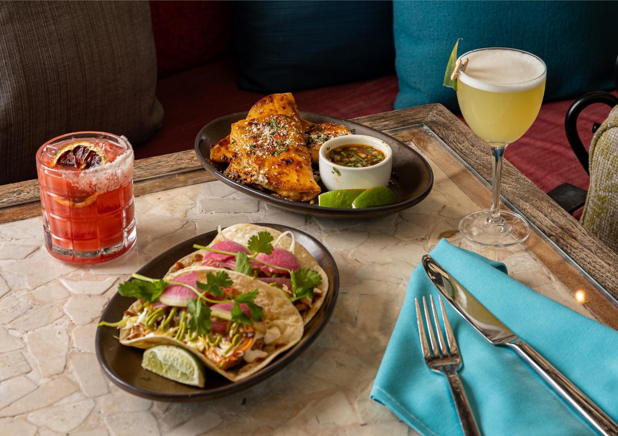 A table with two cocktails and two plates of food