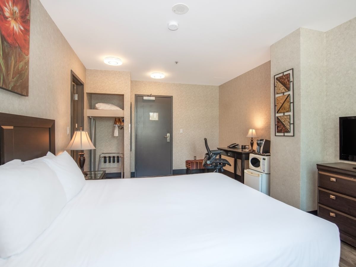 Coast Queen room with a queen bed, a dresser, a TV, and a desk at Coast Lonsdale Quay Hotel