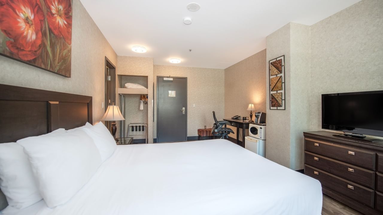 Coast Queen room with a queen bed, a dresser, a TV, and a desk at Coast Lonsdale Quay Hotel