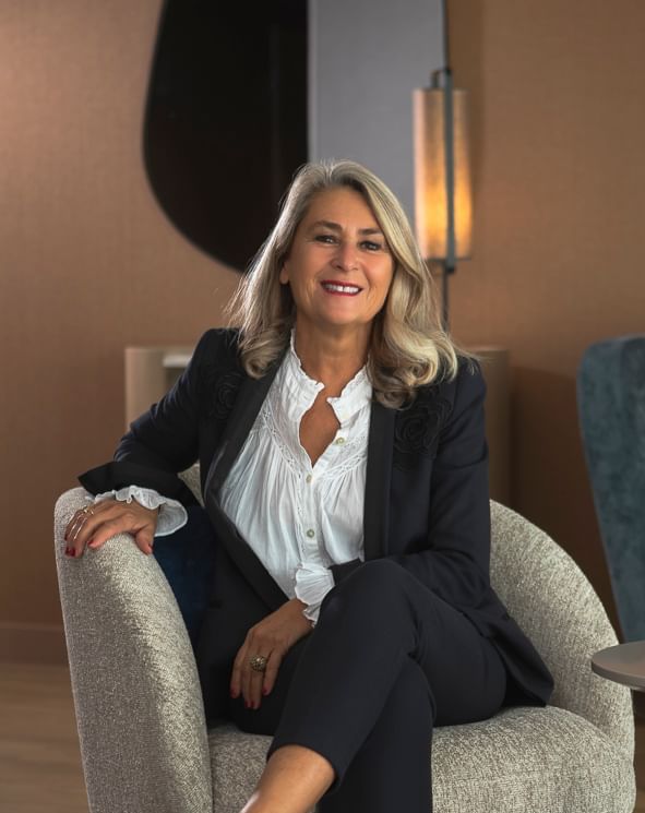 Portrait of a lady in a suit posing on a lobby lounge at Oceania Hotels