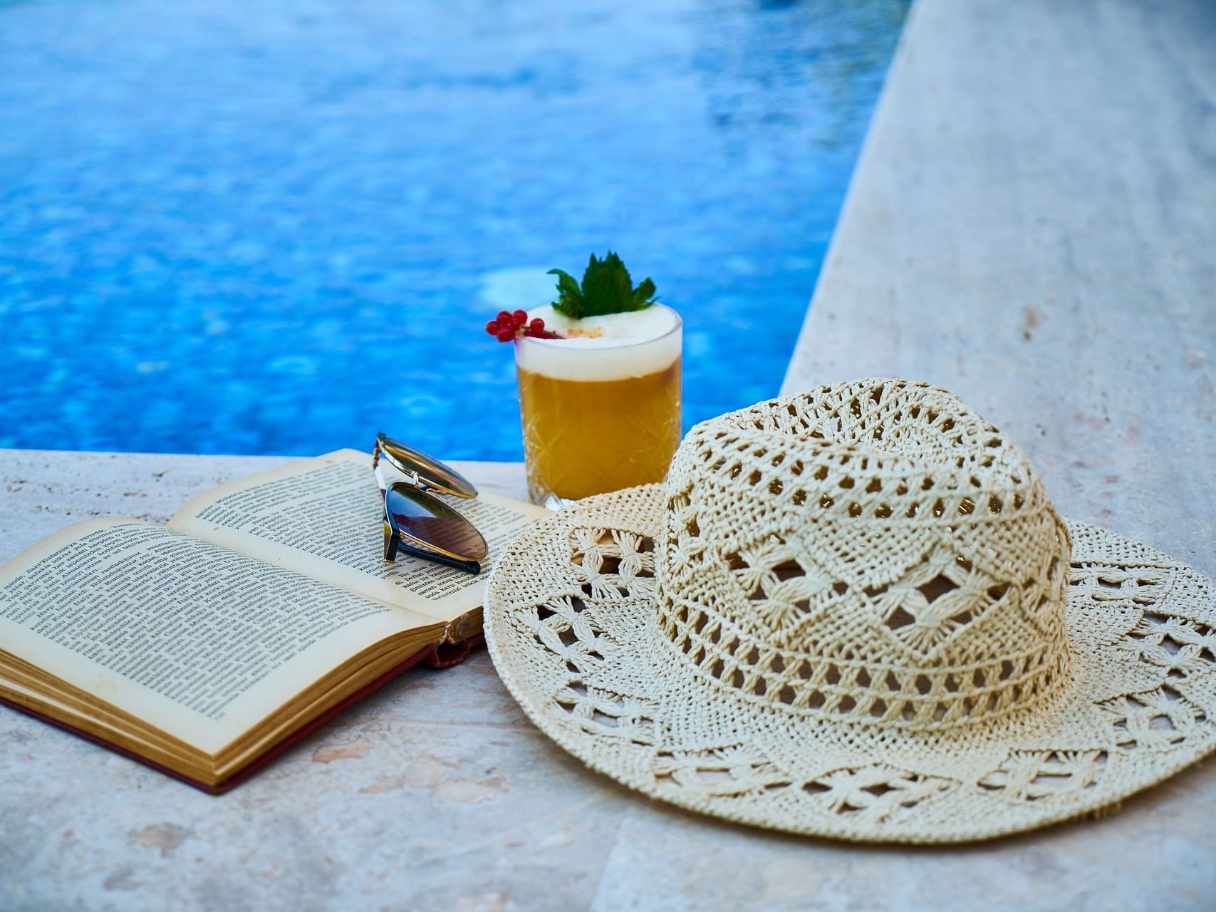 A Hat, book, & a drink on the pool corner at Bay Club Hotel