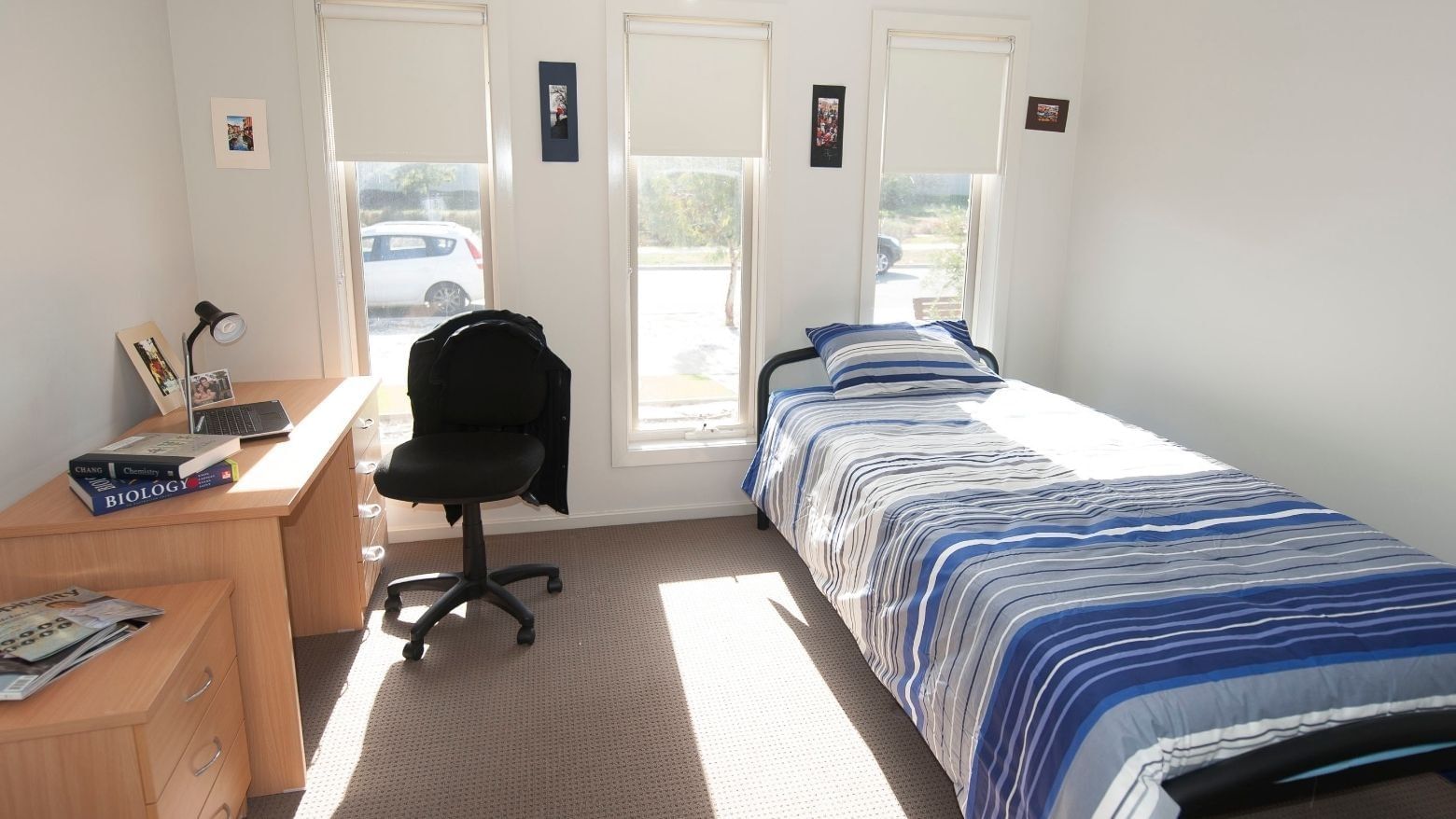 Bedroom with bed, desk, chair, and window at La Trobe University Regional Housing.