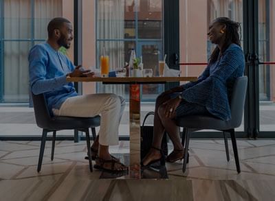 Two people sitting at a table with drinks at Azalai Hotel Ouagadougou