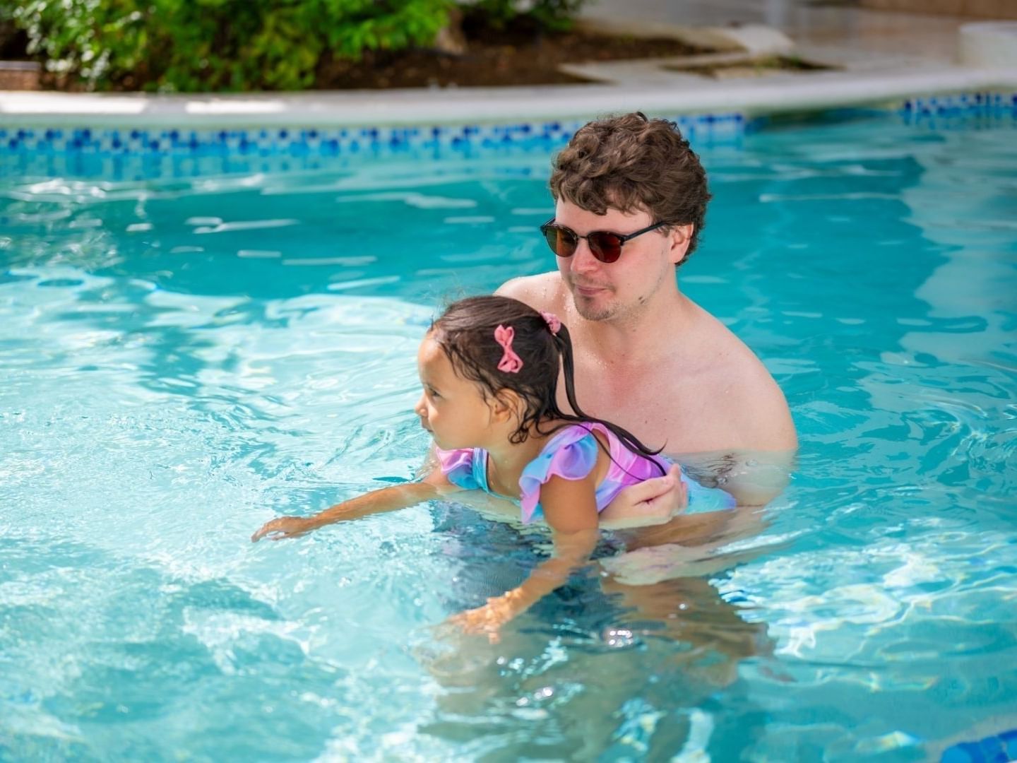 Father holding daughter in pool at Savannah Beach Hotel.