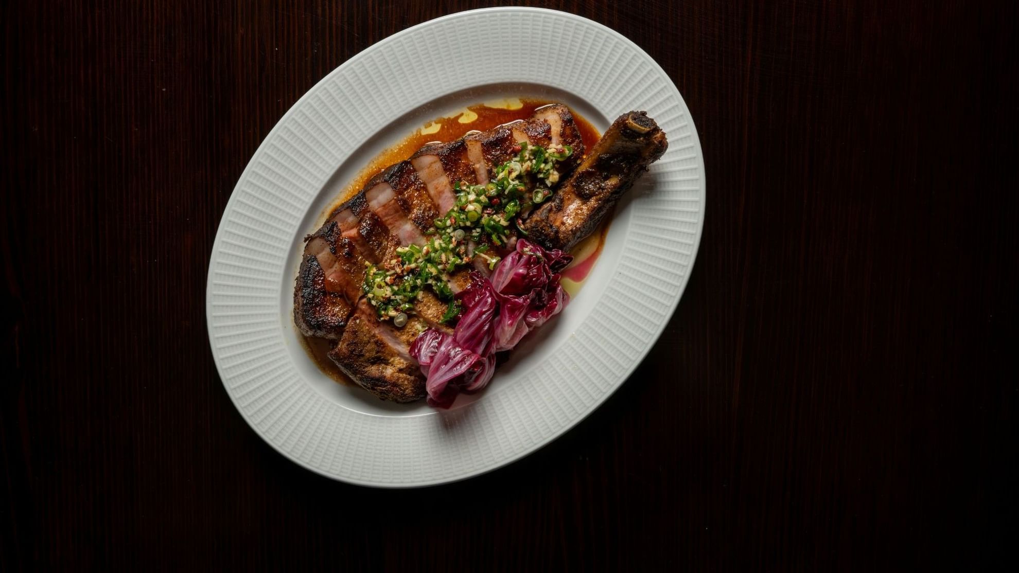 Grilled steak with herb topping and pickled onions on a white plate for NRL Grand Final Dining