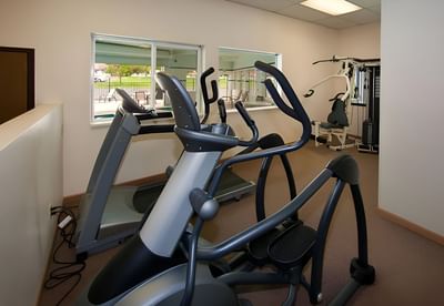 Fitness room at Moab Valley Inn with an elliptical, treadmill, and large windows letting in natural light