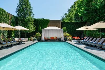 Outdoor pool with loungers by a cabana at The J House Greenwich, a luxury hotel in Fairfield County for business travelers
