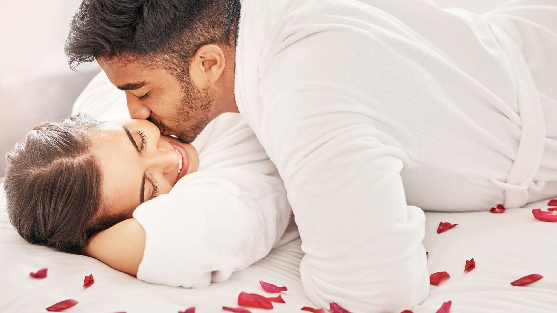 Couple in bathrobes sharing a tender moment on a bed with rose petals, promoting the Soulful Harmony treatment.