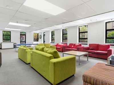 Communal lounge area with couches, tables, and a television at UniLodge Stafford House.