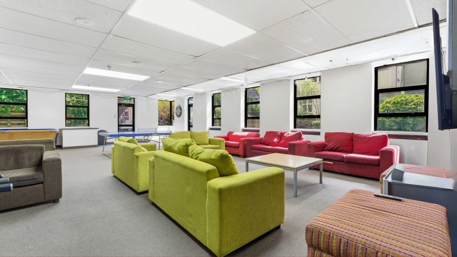 A lounge area with colorful couches, a coffee table, and a TV mounted on the wall.