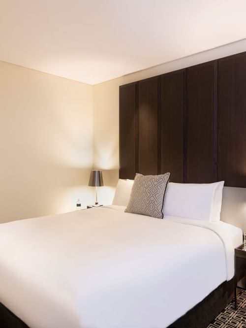 Junior Suite MyBed with door open to en suite and beautiful flowers on the bedside.