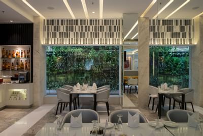 Dining area in The Glass House with a garden view at Eastin Residences Vadodara