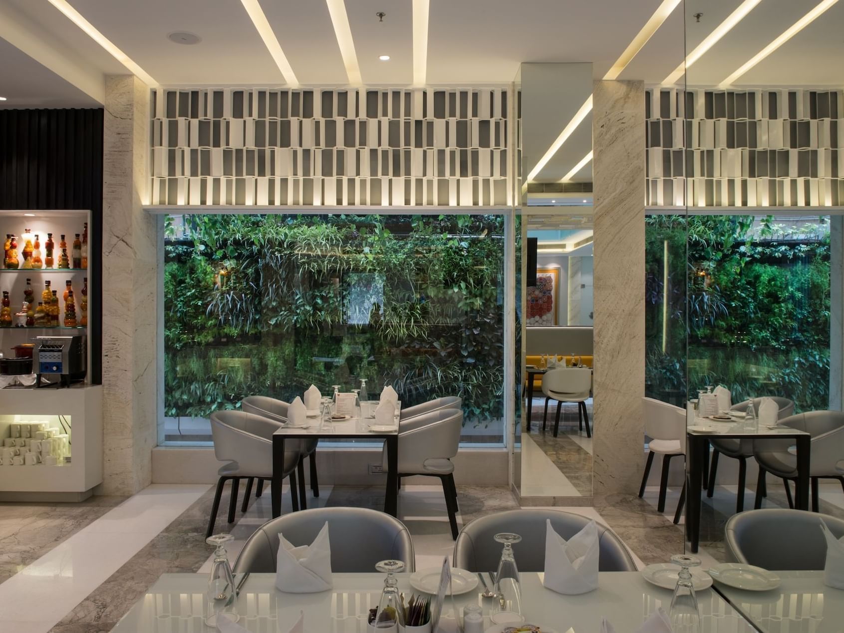 Dining area in The Glass House with a garden view at Eastin Residences Vadodara