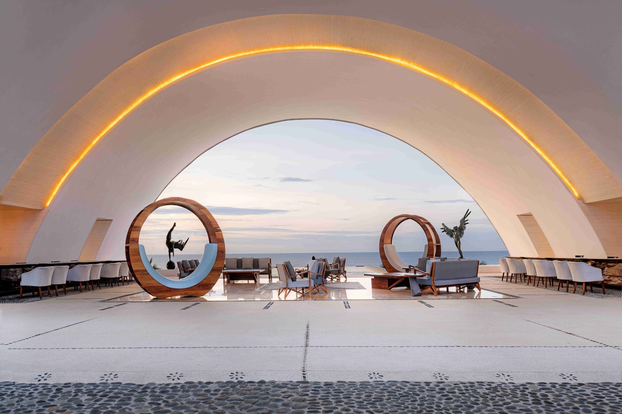 Outdoor lounge with circular sculptures and ocean view under a curved ceiling at Marquis Los Cabos