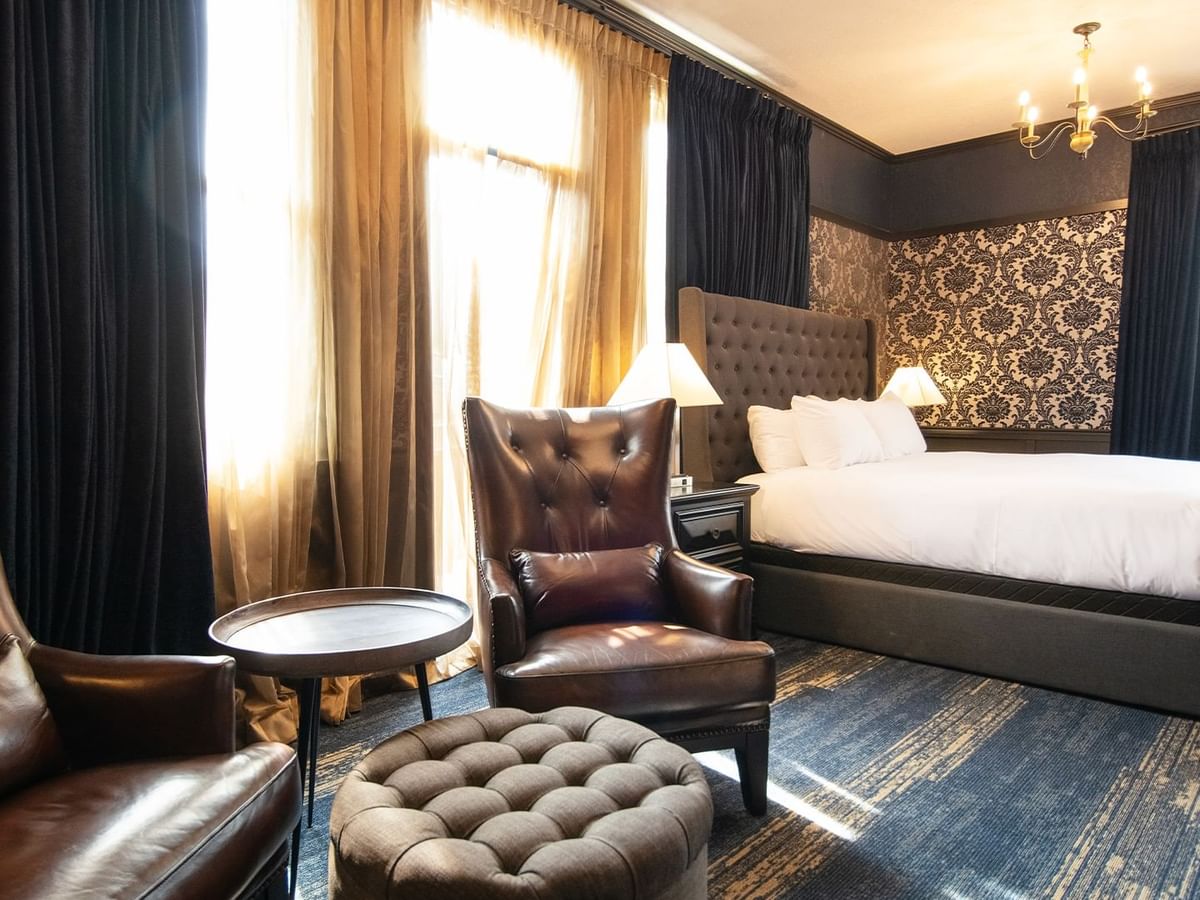 Hotel room with king bed, armchair, coffee table, and window