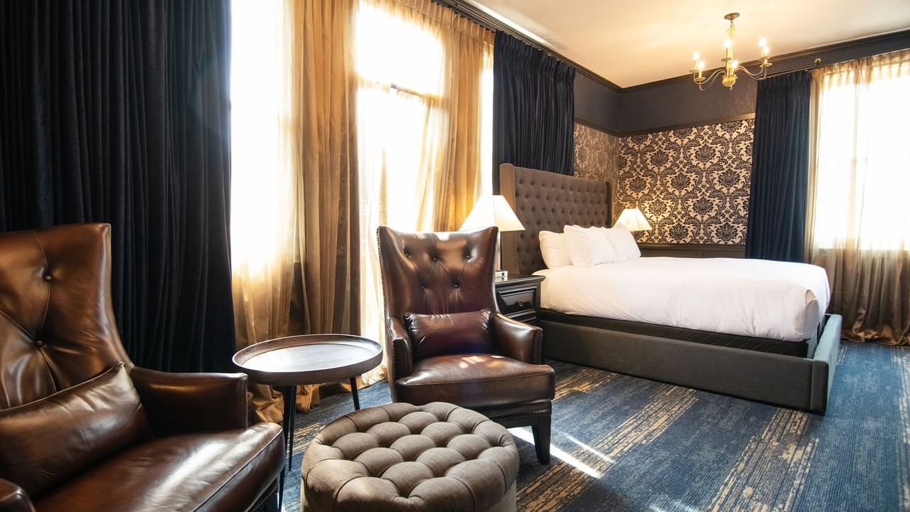 Hotel room with king bed, armchair, coffee table, and window