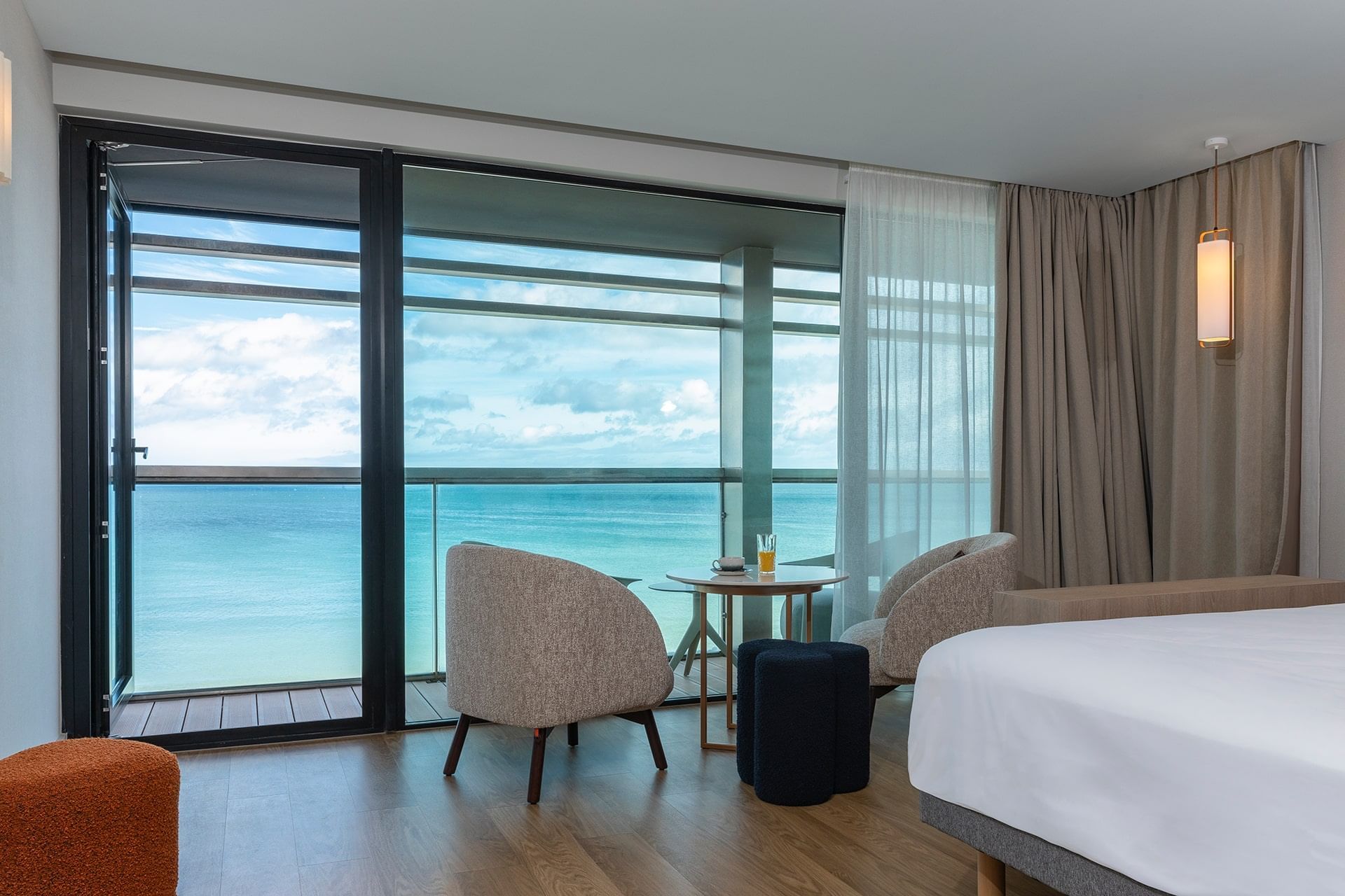 Intérieur et décoration d'un lit king-size avec fauteuils et table basse avec vue sur la mer dans une chambre à l'Oceania Saint-Malo