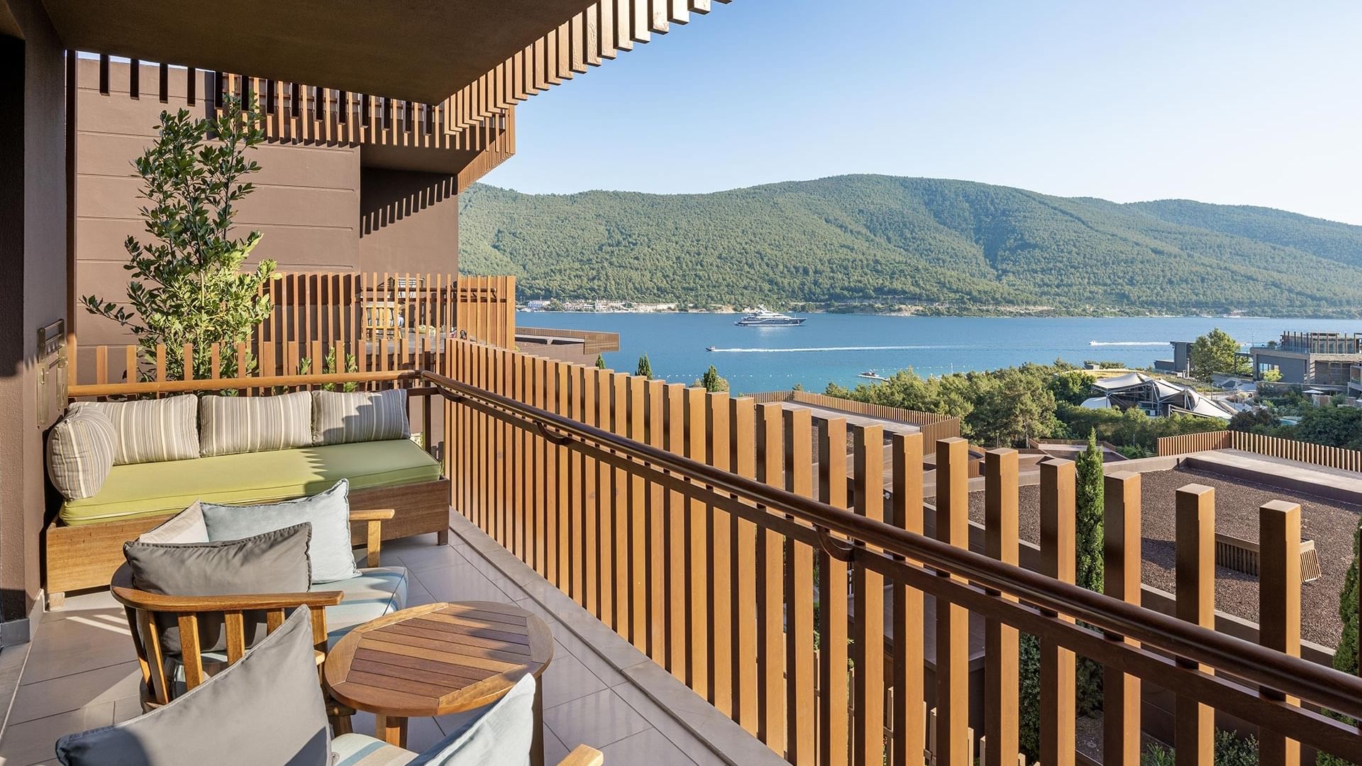 Titanic Luxury Collection Bodrum’da ahşap mobilyalı, deniz ve tepe manzaralı Family Suite balkonu.